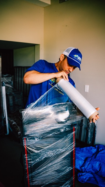 A Homeboy Movers crew member wrapping a dresser in clear plastic shrink wrap