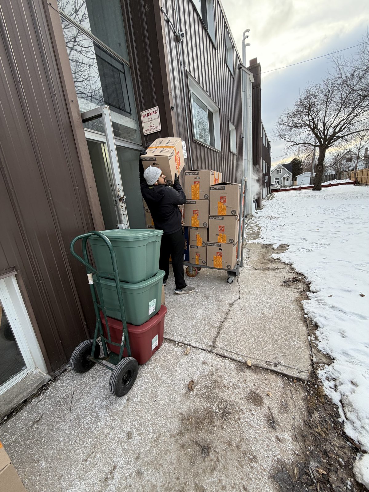 A Homeboy Movers crew member carrying a box to the door on a winter moving day