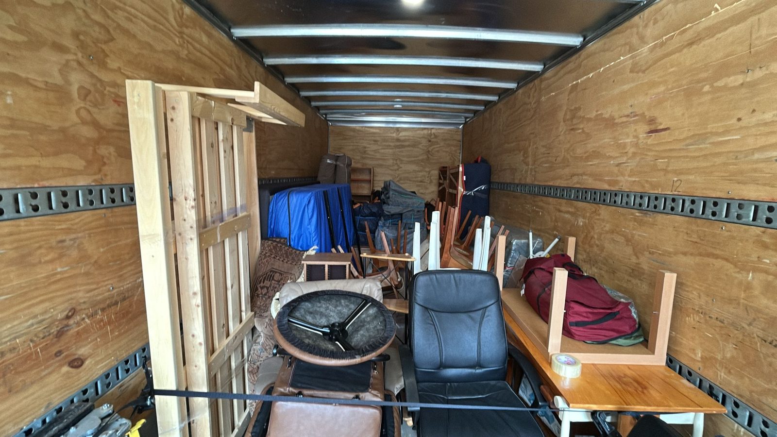 Inside a Homeboy Movers truck neatly loaded with furniture, chairs and a table, secured for transport