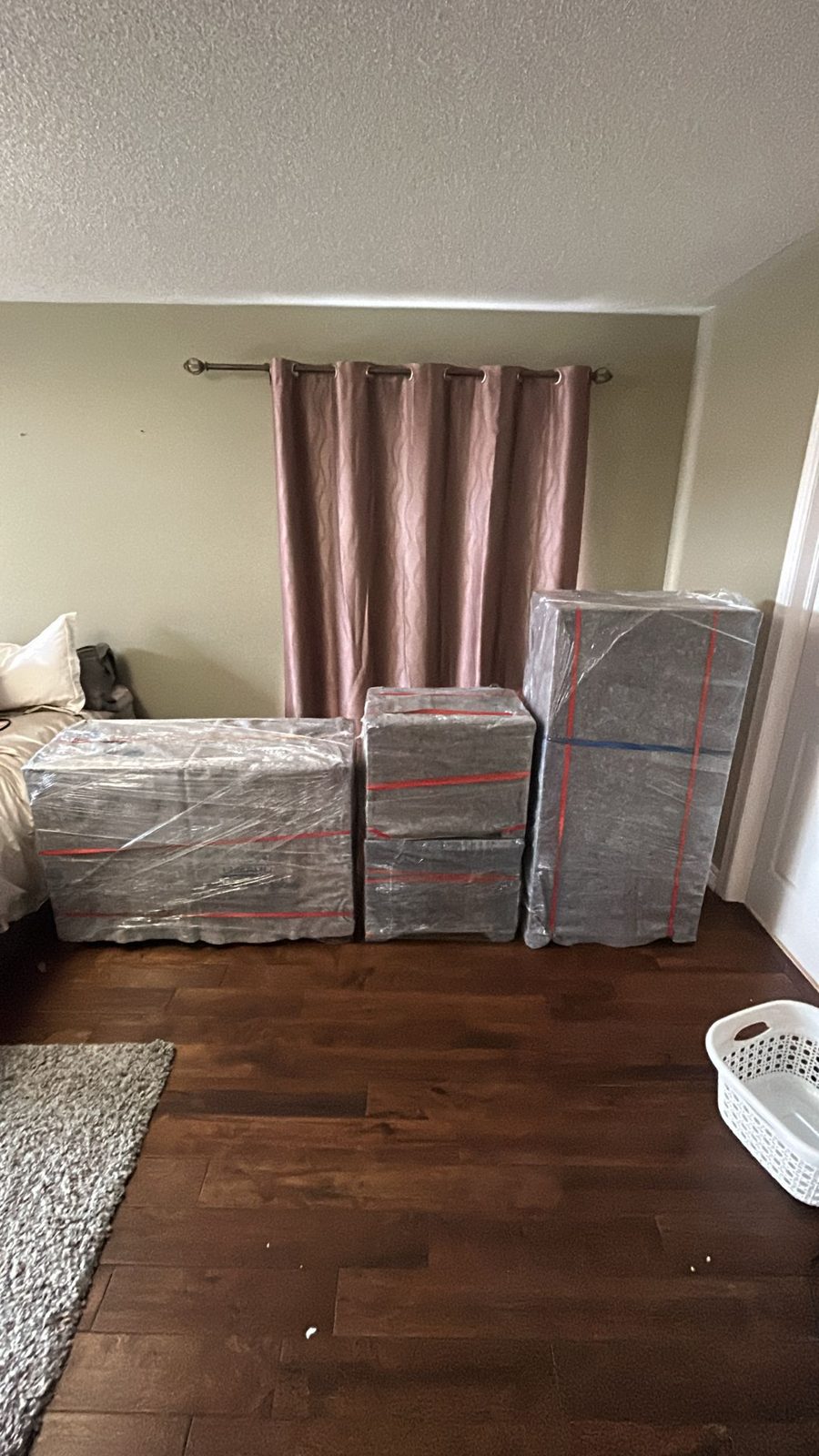 Dressers shrink-wrapped and protected in a bedroom, ready for the move