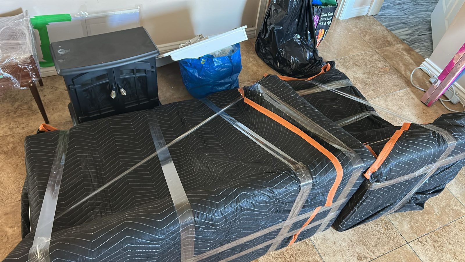Furniture wrapped in padded moving blankets and secured with straps, set out in a home ready to load