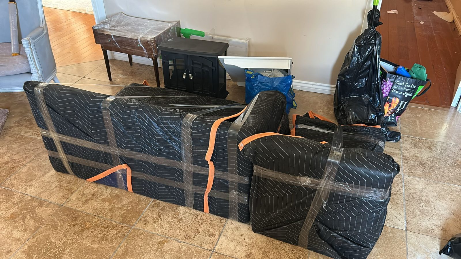 Furniture bundled in moving blankets and orange straps on a Homeboy Movers job